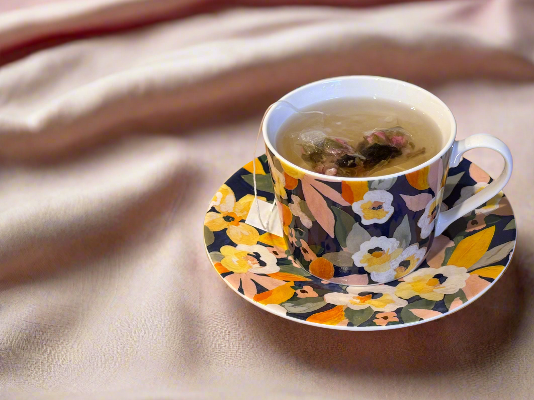 Floral teacup and saucer with tea on a rose beige linen background
